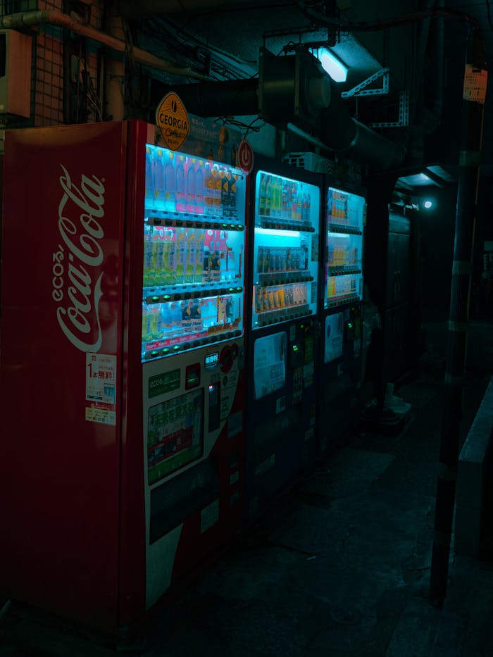Vibrant neon vending machines in a dimly lit urban alley at night, showcasing a techy, futuristic vibe.