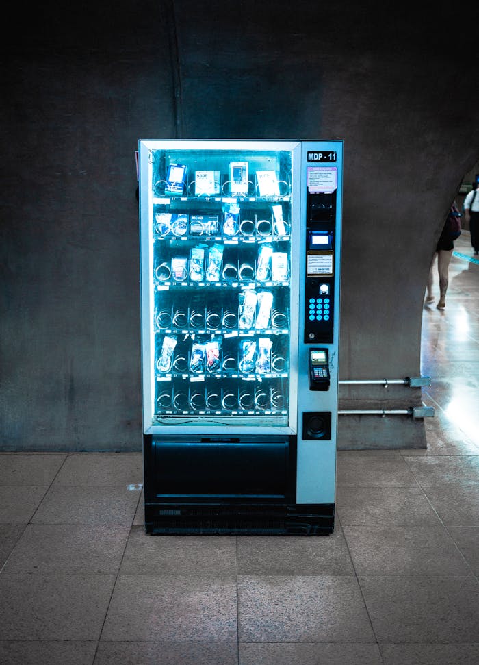 A glowing vending machine stocked with various products in a dimly lit corridor.